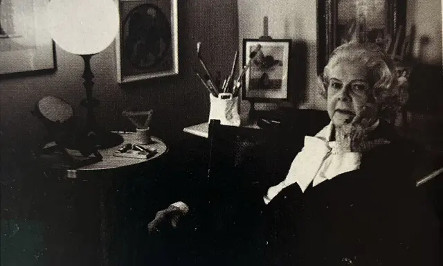 Colette Gueden, artiste peintre, dans son atelier, entourée de ses œuvres et de son matériel.