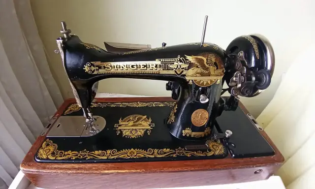 Machine à coudre Singer ancienne, noire et dorée, sur son socle en bois. Le numéro de série est visible pour une estimation.