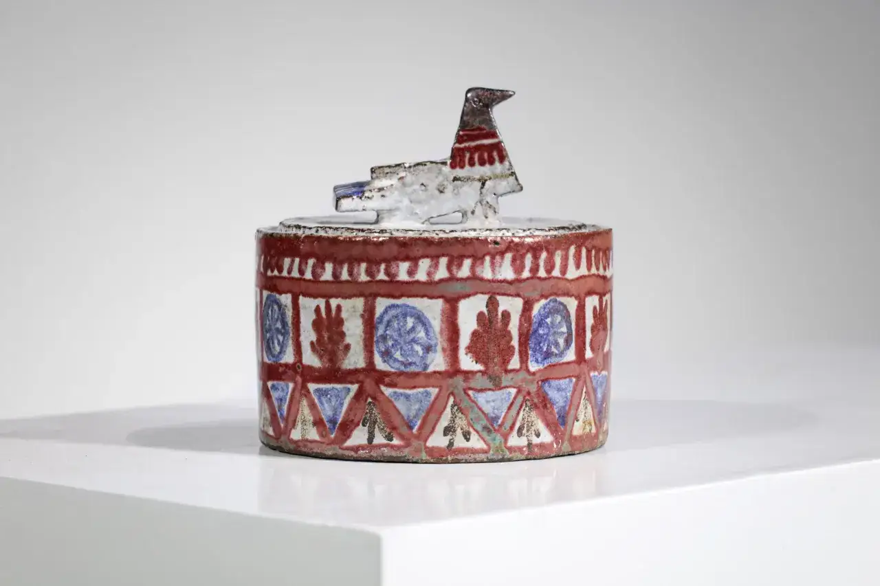 Boîte en céramique de Jean Derval ornée d'un oiseau stylisé et de motifs géométriques rouges, bleus et blancs.