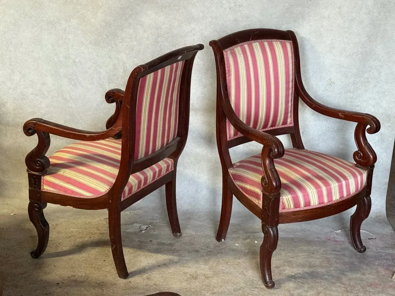 Deux fauteuils en bois sombre, style &eacute;poque Restauration, avec coussins &agrave; rayures roses et cr&egrave;me.