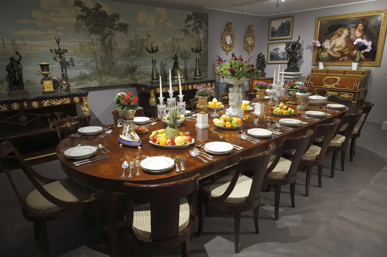 Salle à manger somptueuse, table dressée dans le style directoire, fruits frais, vaisselle raffinée, tapisserie murale paysage, ambiance d'époque.