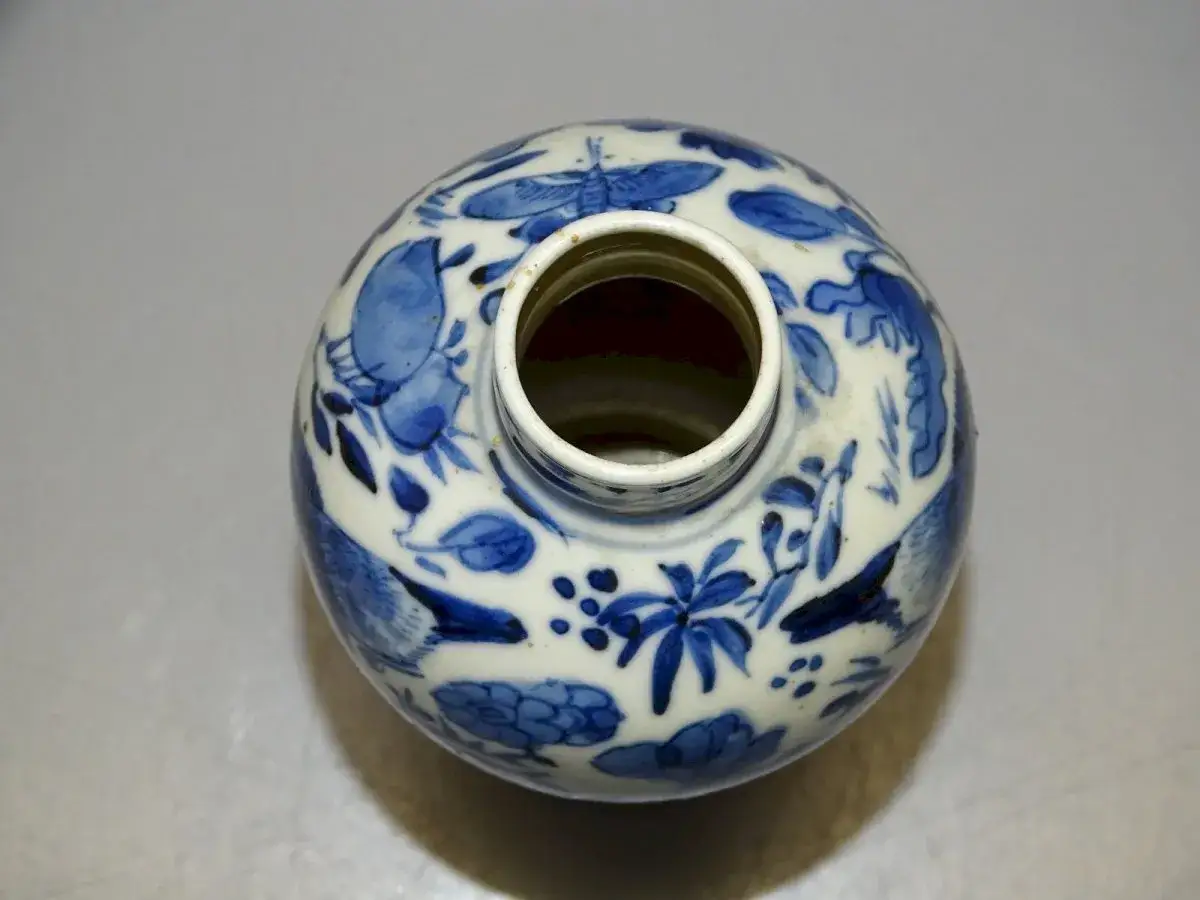 Vue de dessus d'un signature vase chinois ancien, orn&eacute; de motifs bleus de fleurs et d'oiseaux sur fond blanc.