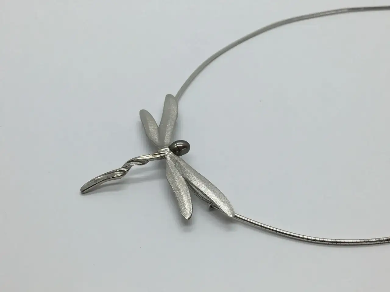 Pendentif libellule art nouveau en argent, avec une perle noire pour le corps, sur un fin collier.