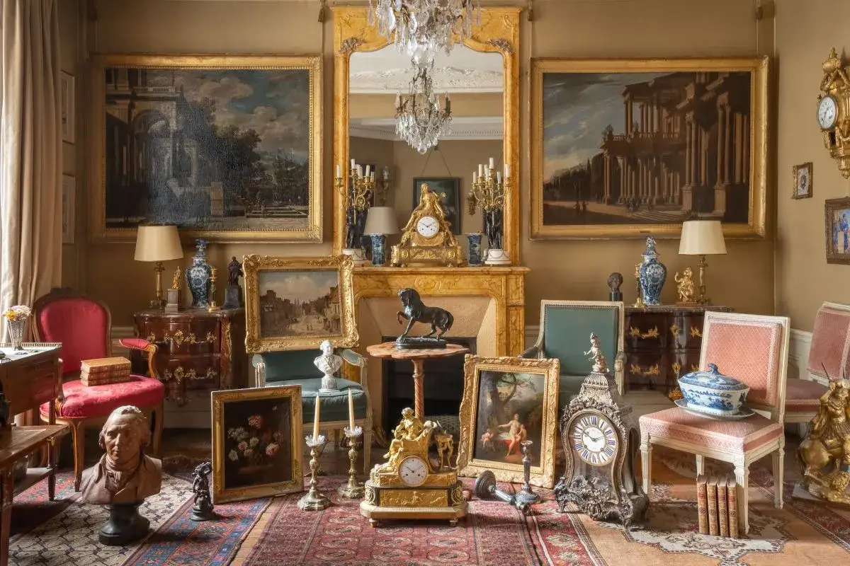 Pi&egrave;ces d'antiquit&eacute;s, peintures, horloges et bustes dans un salon. Un inventaire de mobilier de succession est en cours pour estimer le co&ucirc;t.