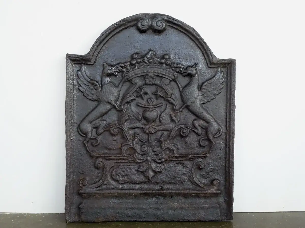 Plaque de cheminée en fonte ornée de griffons et d'un cœur, idéale pour une estimation.