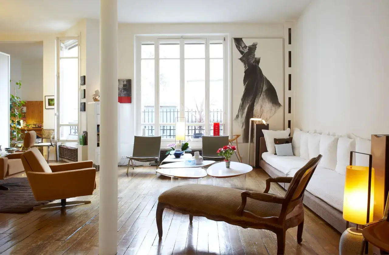 Salon lumineux avec parquet ancien, canap&eacute; blanc, fauteuils design et une m&eacute;ridienne. Les meubles anciens reviennent &agrave; la mode, apportant une touche d'&eacute;l&eacute;gance intemporelle.