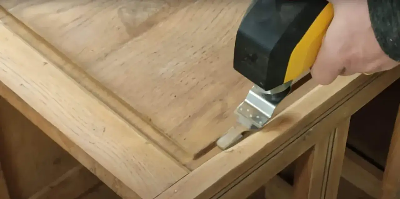 Utilisation d'un outil oscillant pour comment poncer un meuble avec des moulures. La lame s'ins&egrave;re dans les recoins pour un pon&ccedil;age pr&eacute;cis.