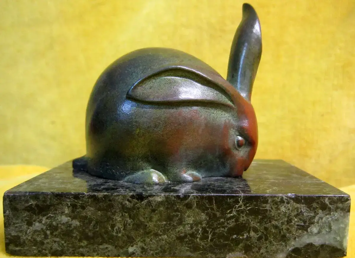 Lapin en bronze, &oelig;uvre d'Ir&eacute;n&eacute;e Rochard, pos&eacute; sur un socle en marbre vert vein&eacute;. Le lapin est accroupi, une oreille dress&eacute;e.