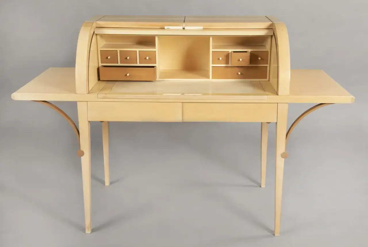 Bureau secrétaire en bois clair, avec un abattant roulant et de nombreux tiroirs. Un beau meuble de rangement signé Hurel Mobilier.