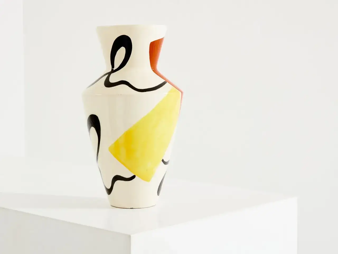Vase aux formes abstraites, jaune et rouge, avec des volutes noires, dans le style de Roland Brice.