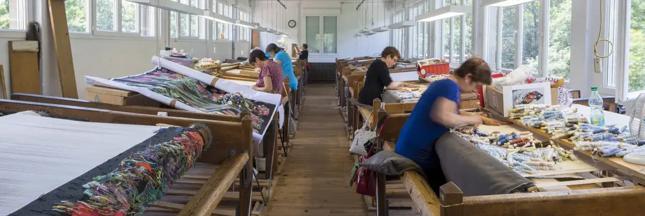 Dans un atelier, des femmes tissent des tapisseries à Aubusson. L'artisanat d'art de robert four aubusson prend vie.