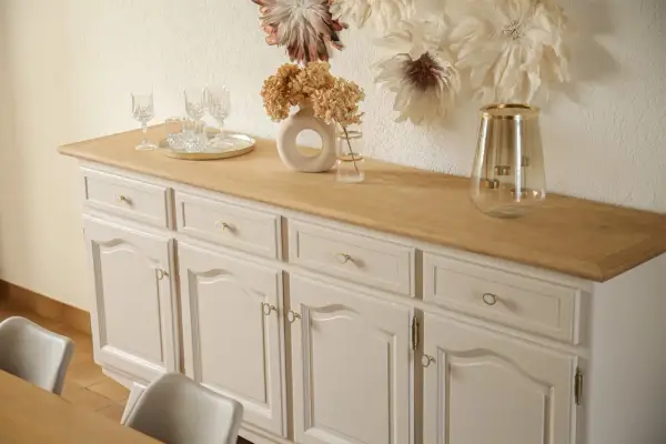 Buffet année 30 repeint, avec un plateau en bois clair. Des verres et un vase décorent le dessus.