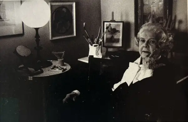 Colette Gueden, artiste peintre, dans son atelier, entourée de ses œuvres et de son matériel.