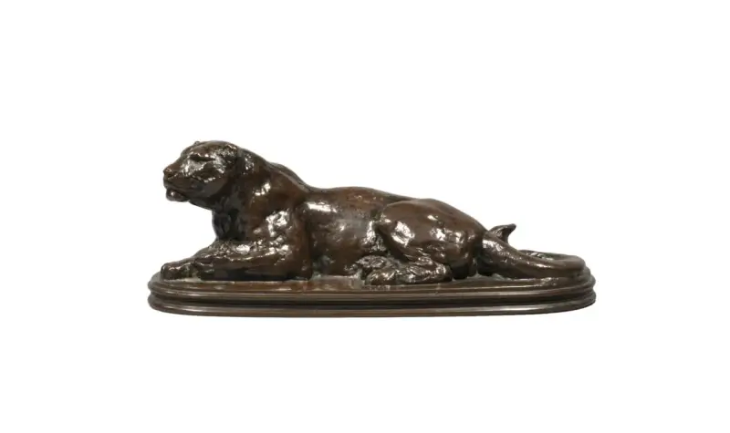 Sculpture en bronze d'un lion couché, œuvre du sculpteur Barye. La signature est discrète.